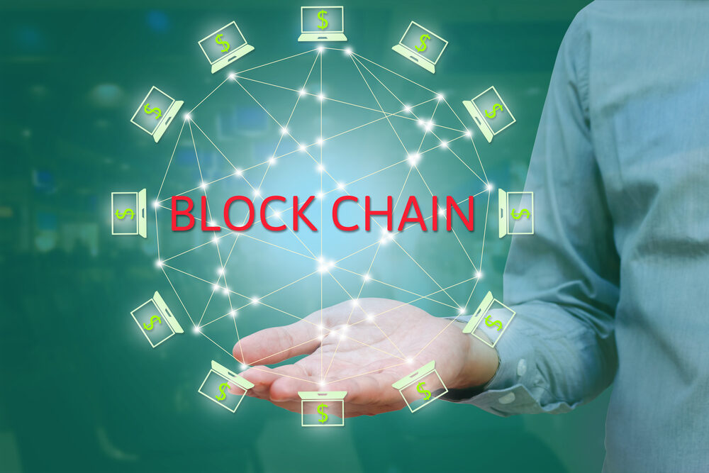 A hand holding a digital wheel of blockchain in green color network of computers