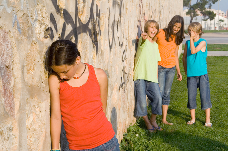 school bully or bullies bullying a sad girl leaning against a wall full of graffiti