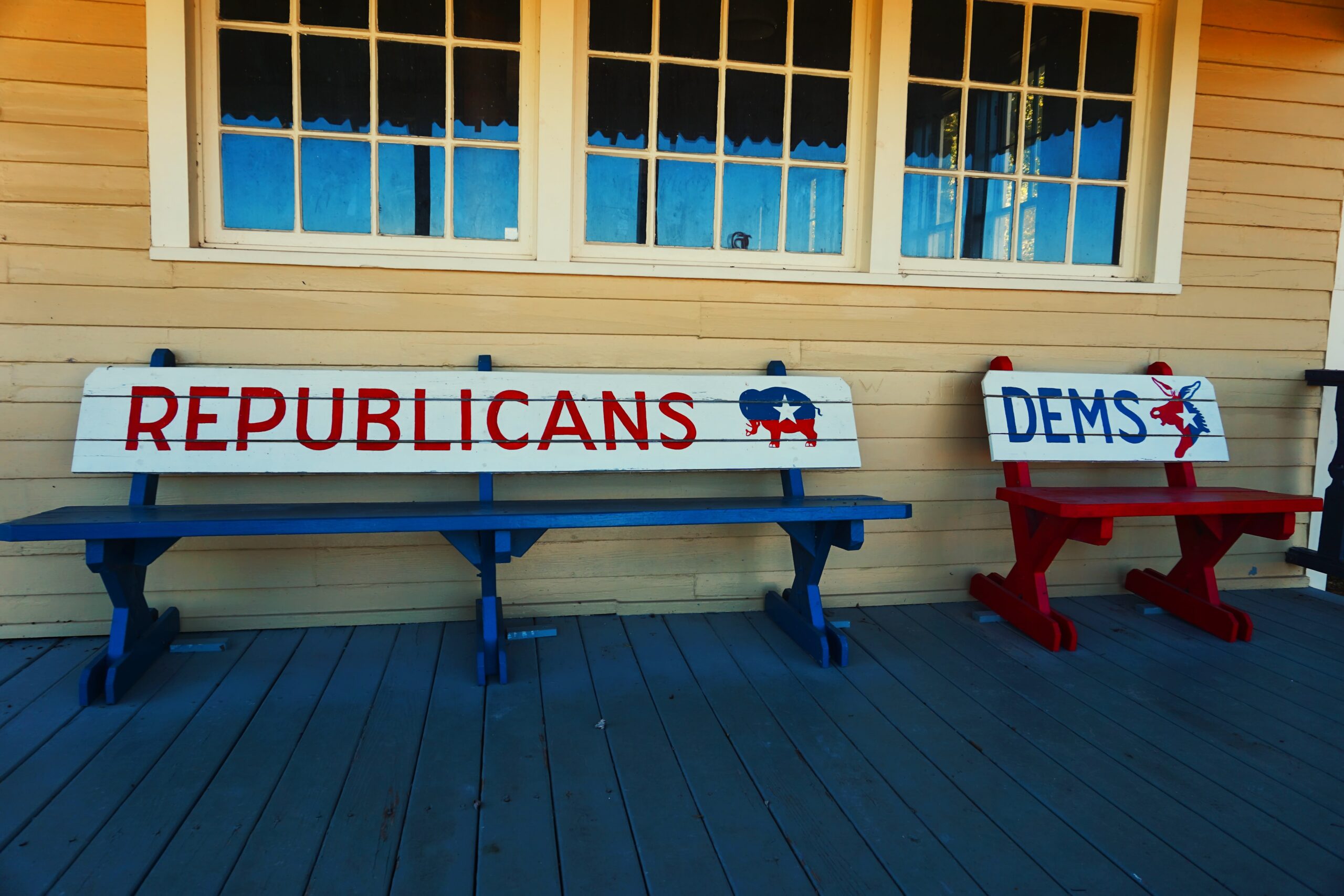 rural town sitting benches outside of voting location reading Republican with Red color and Democrats with blue color.