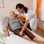A senior disabled citizen is receiving assistance from a friendly and smiling nurse.