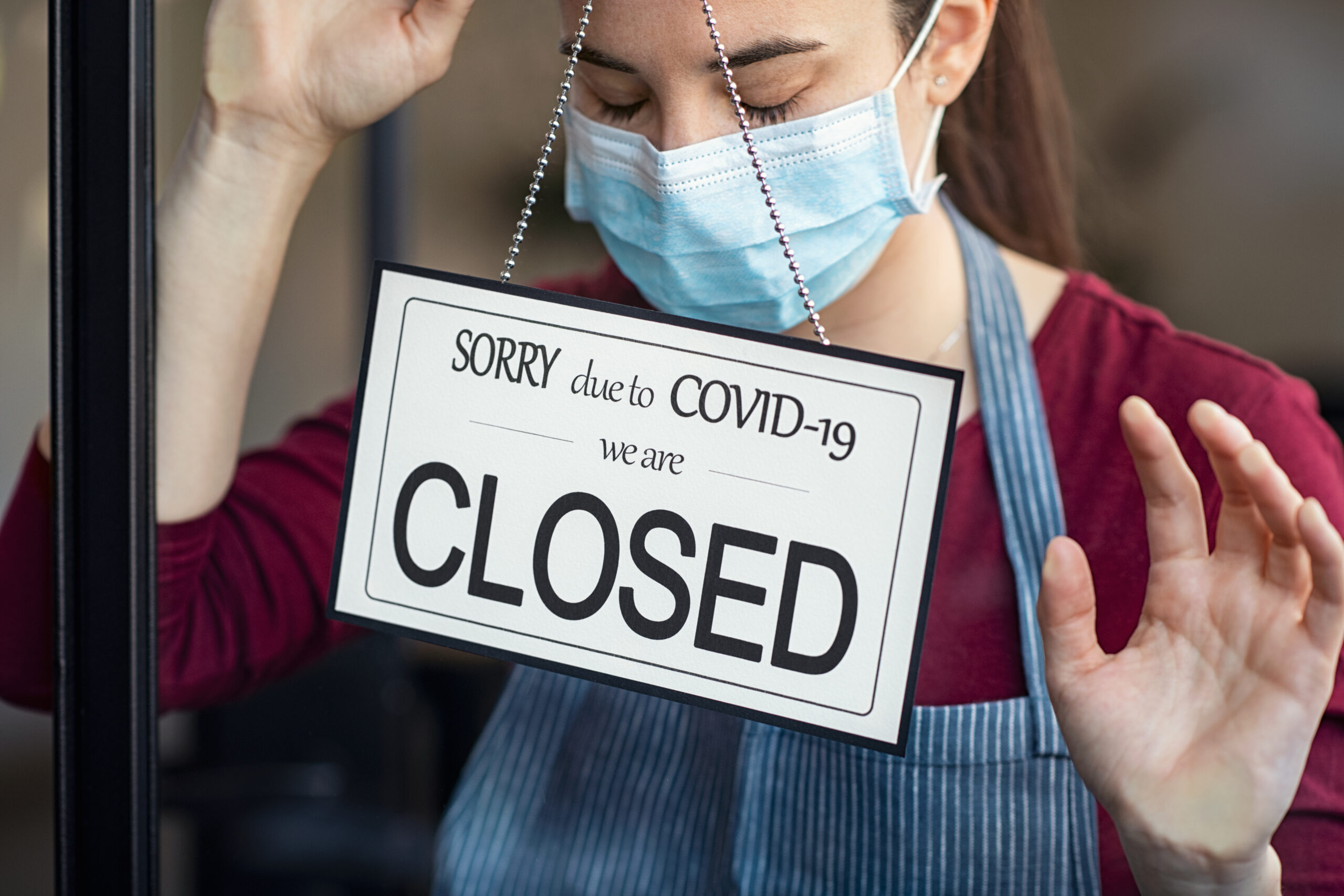 A business woman is wearing a covid 19 mask to protec her self from contamination of Covid -19. She is sad and stressed due to business closing.